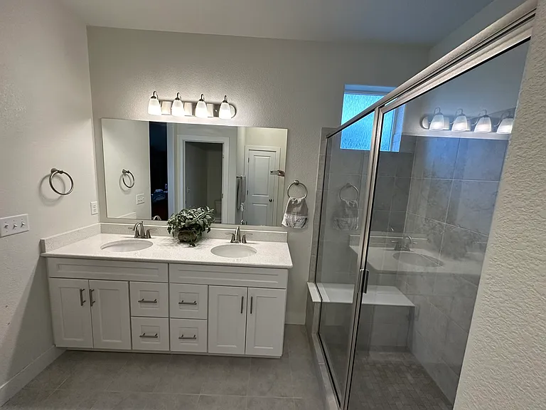 Primary bath with double sinks and sit-down tile bench in shower