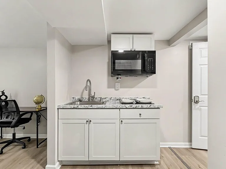 Compact kitchenette with granite-look counters, stainless sink, and over-the-range microwave for easy everyday meal prep.