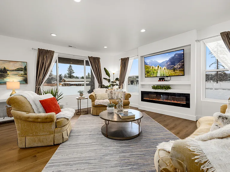Beautifully designed living area perfect for entertaining and relaxing, featuring a sleek modern fireplace, large flat-screen TV, and breathtaking mountain views from every window.