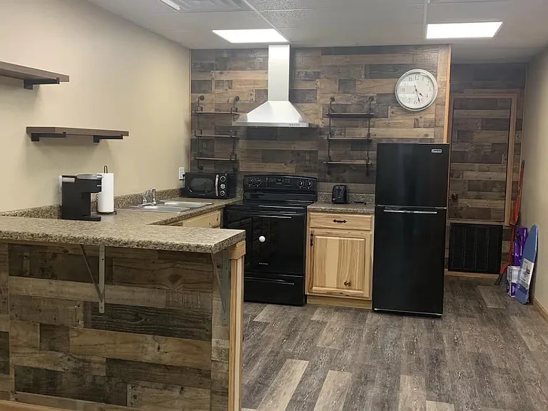 Functional shared kitchen with peninsula counter, open shelving, range with hood, and full-size refrigerator.