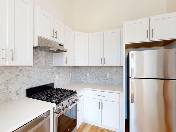 Kitchen with cabinets, refrigerator, stove, range hood, and sink