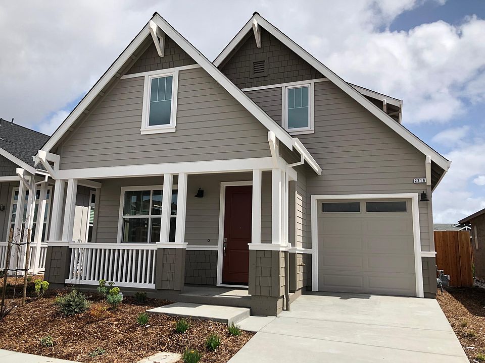 Front of home with porch and 2-car tandem garage. Path to backyard has been added; landscaping has matured.