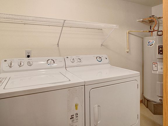 A full size washer and dryer in a closet off the living room next to the water heater