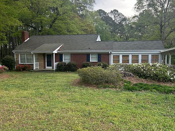 Front of house.. carport to right with asphalt driveway and gazebo and storage building to right and back of this photo