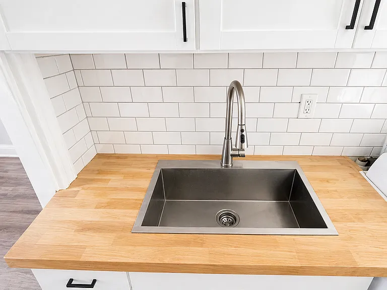 Refreshed kitchen with new fixtures, cabinets, subway tile backsplash.