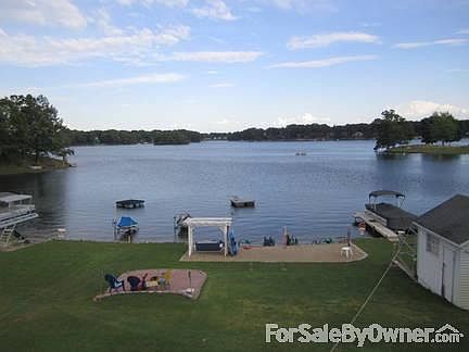 View of the Lake from Upper Deck
						:
						Paved fire pit, sandy beach, and large shed.