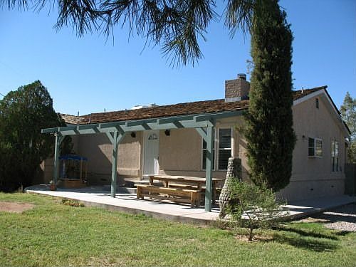 Single story ranch house on an acre with several mature trees.