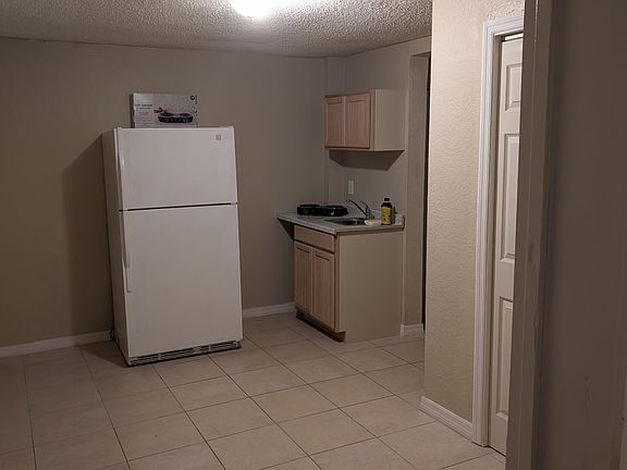 Kitchenette with refrigerator, sink, 2 burner countertop stove, and storage.