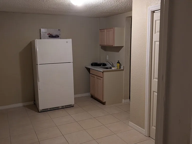 Kitchenette with refrigerator, sink, 2 burner countertop stove, and storage.