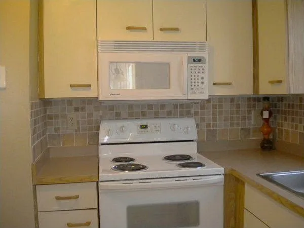 Kitchen has new flooring, lighting and decorative backsplash.