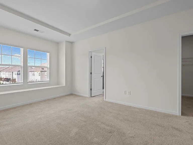 Large master suite features window seat, tray ceiling and oversized walk-in closet with master bathroom.
