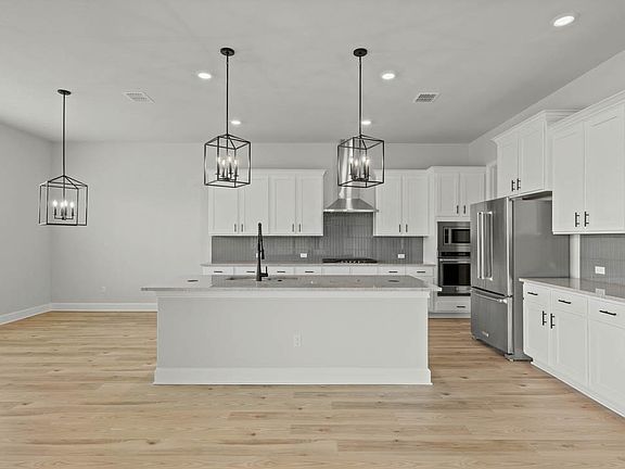 The kitchen has white wood cabinetry.