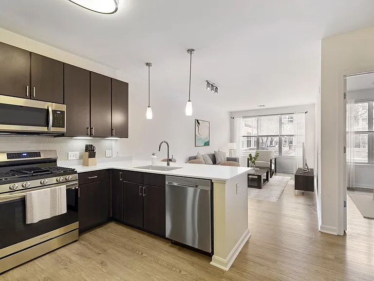 Renovated Package I kitchen with stainless steel appliances, white quartz countertops, espresso cabinetry, beige tile backsplash, and hard surface flooring