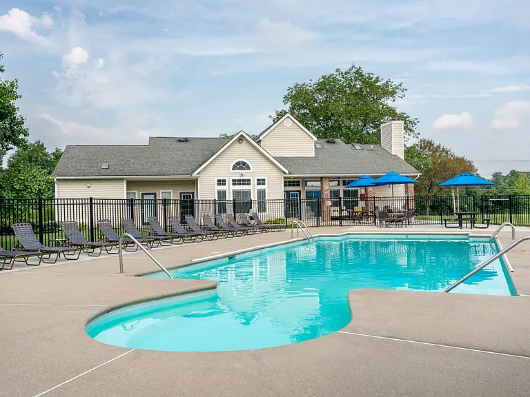 Dive into the inviting pool at Windridge, complete with lounge chairs, shaded tables, and a serene, private setting.