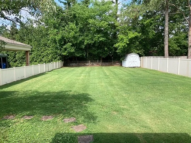 Back yard with privacy fence and storage building.
