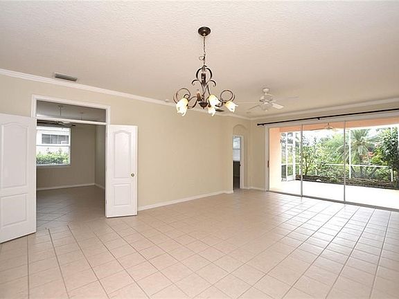 Spacious living and dining area with nearby den/office and triple sliders to the screened lanai.