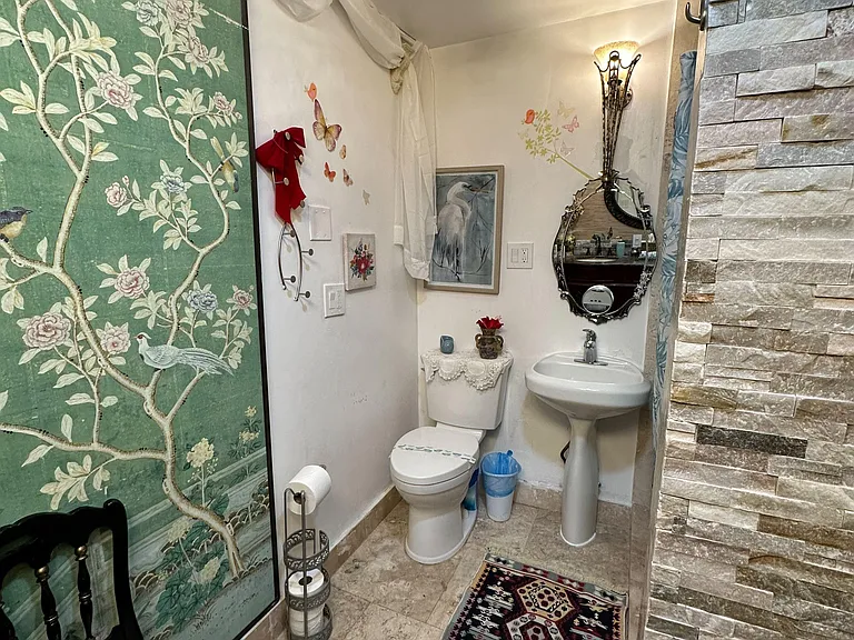 Compact half bath with pedestal sink, decorative mirror, and tile flooringconvenient for guests and daily use.