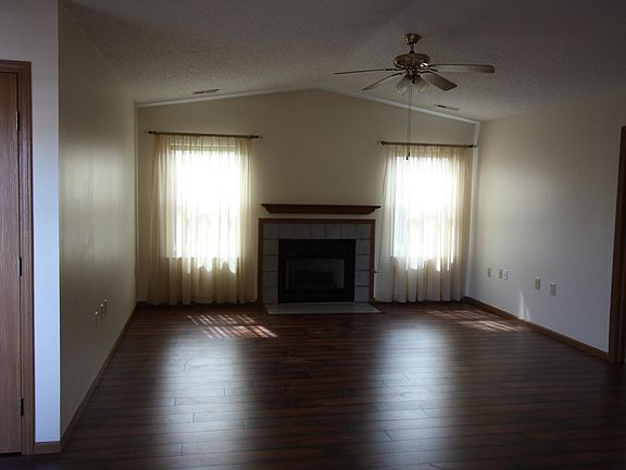 Living Room with laminate floors, gas log fireplace, vaulted ceiling and ceiling fan
