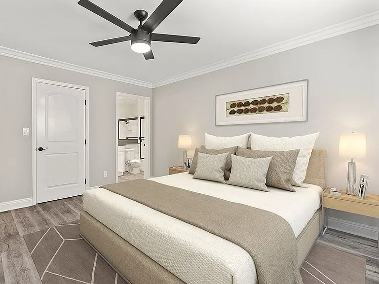 Carpeted bedroom with large mirrored closet and ceiling fan.