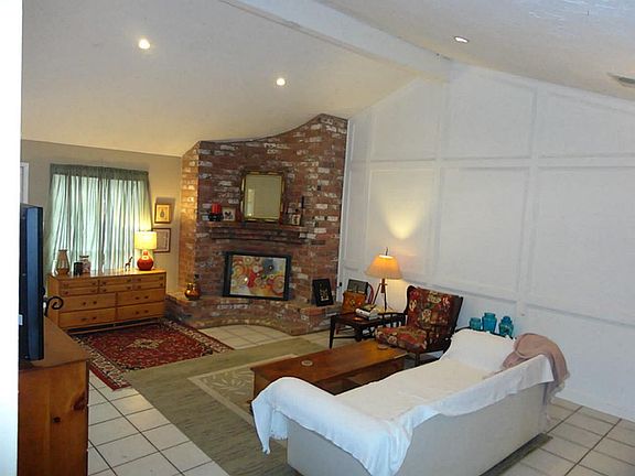 The living room features high vaulted ceilings, large picture windows and a gorgeous brick fireplace.