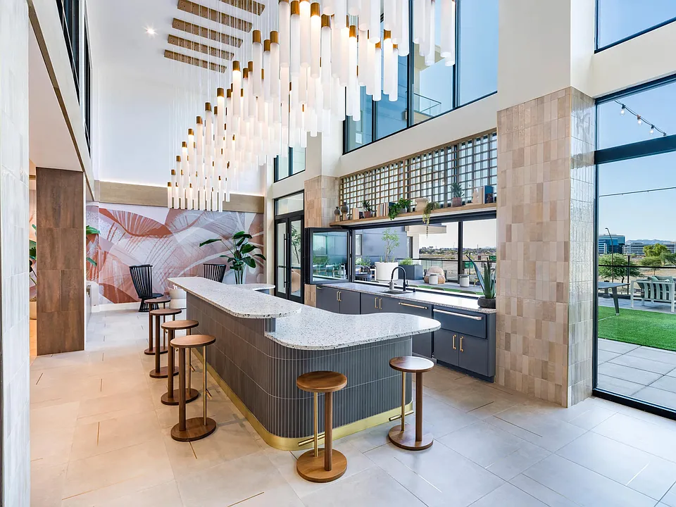 Double-height lounge with a statement island, dramatic pendant lighting, and rooftop views creating a striking space for entertaining and gathering.