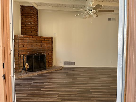 Front entry leads to the family room with cozy brick fire place, ceiling fan, and natural light.