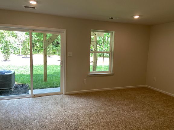 Recreation room with slider door leading to wooded back yard.