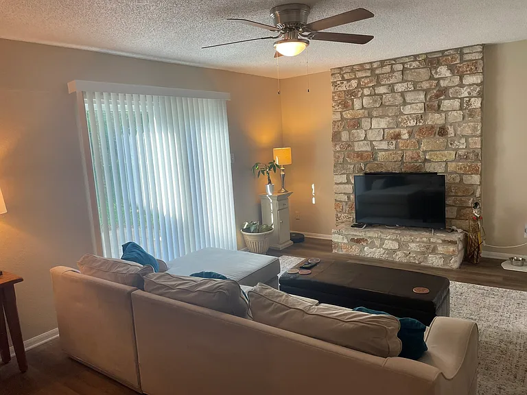 Living area includes new ceiling fan and vertical blinds.