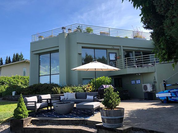 House view from the beach with backyard patio fully equipped with an outdoor seating set, stainless steel grill and more