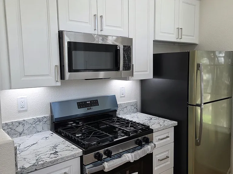 Kitchen counter, stove, oven, microwave and refrigerator.