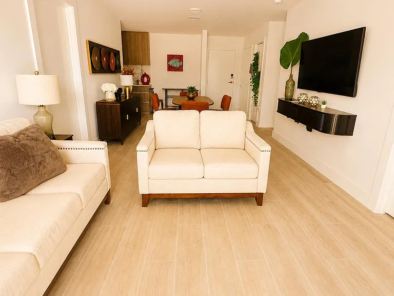 Open-concept living area with comfortable seating, wall-mounted TV, and adjacent dining space on durable tile flooring.