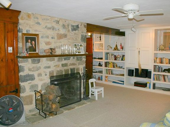 lower level family room with exposed stone walls, fireplace and built-ins
