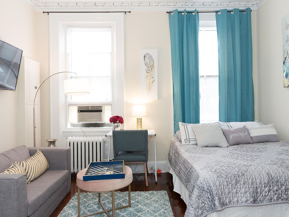 Living space / bedroom showing large windows and sunlight, high ceilings
