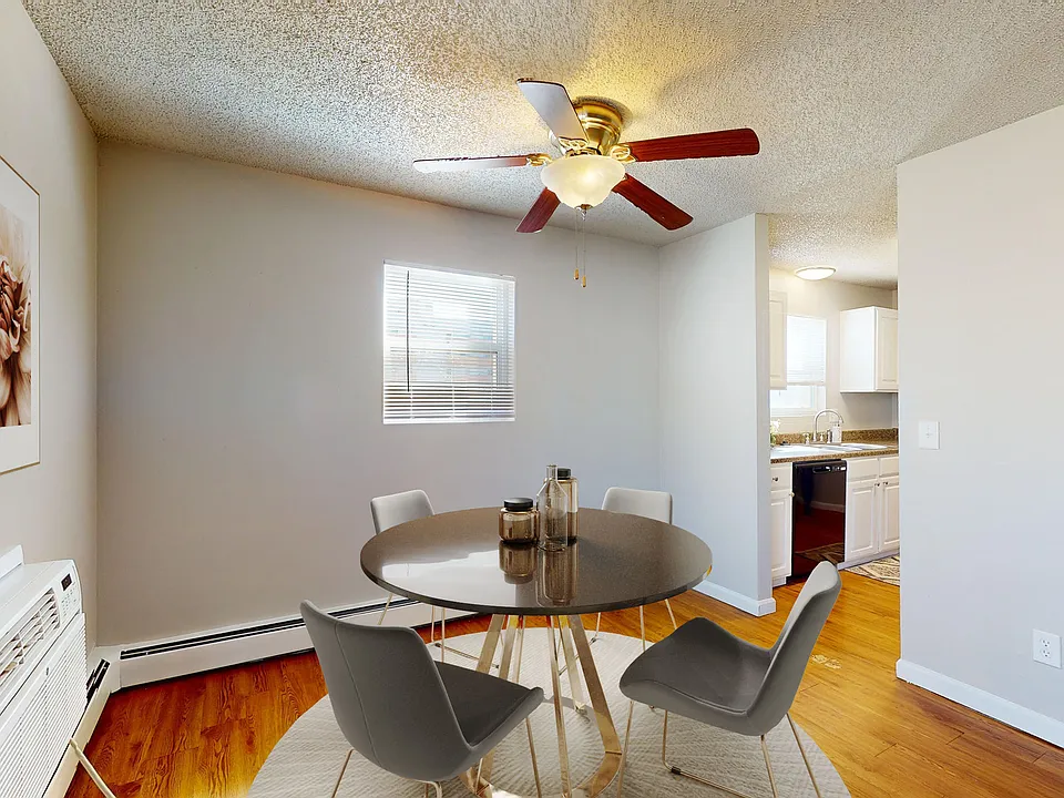Charming dining area with modern round table and stylish chairs, adjacent to a cozy kitchen in a sunlit apartment.