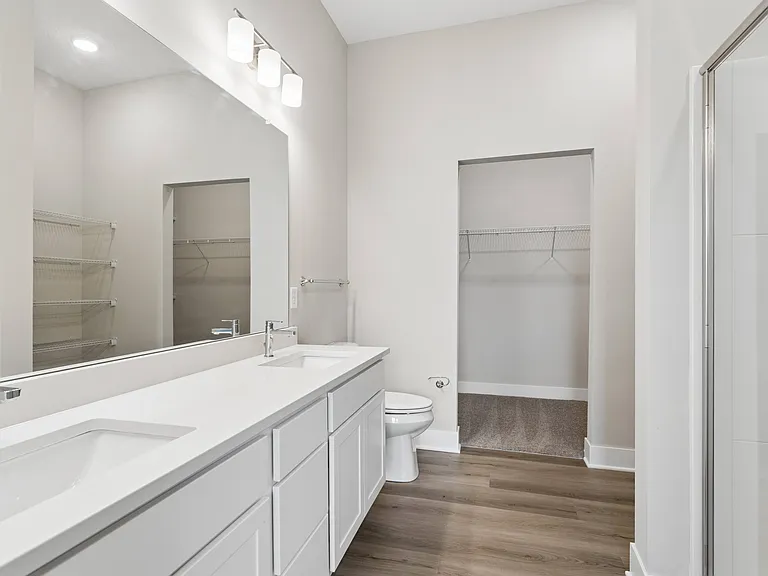 Bathroom with quartz countertops, closet, and bath/shower of an apartment unit.