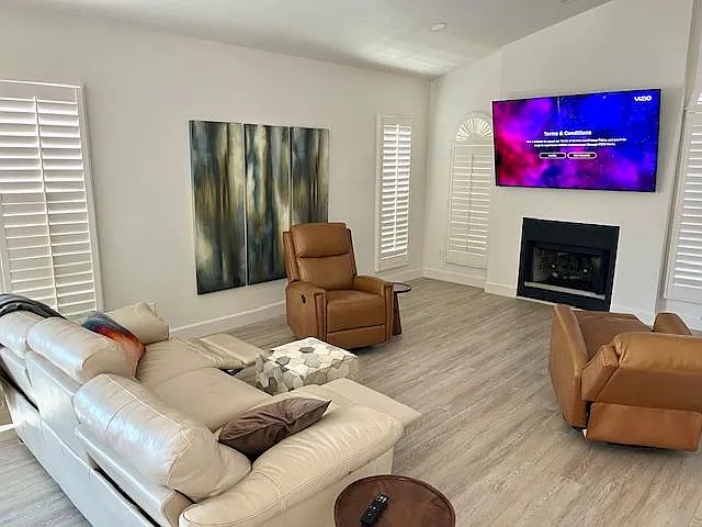 TV room with fireplace, reclining sofa, and reclining rocker swivel chairs.