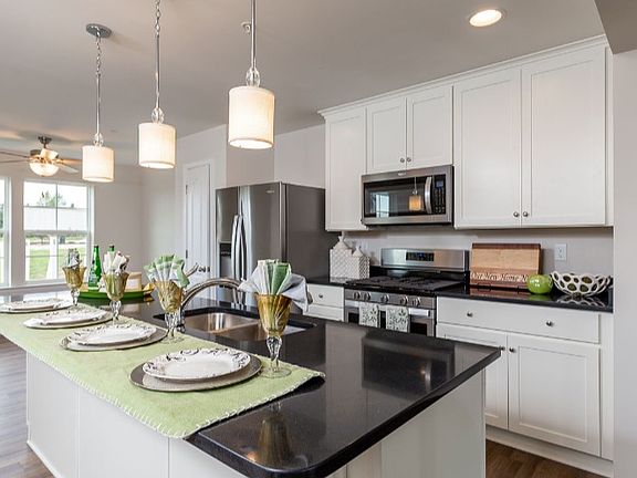 Kitchen with white cabinets, black countertops and stainless steel appliances.