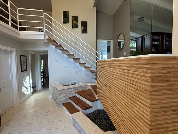 Grand Entry Way with soaring ceilings custom woodwork, limestone floors, and custom wood plank midcentury floating staircase