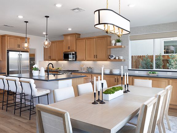 A modern and spacious kitchen with wooden cabinets, a large dining table, and a central island with