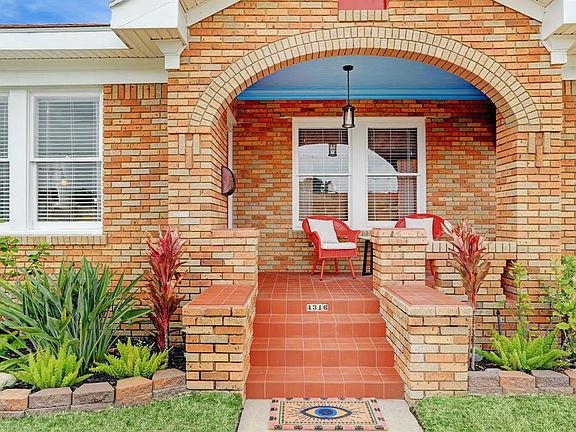 Tiled front steps lead to the tiled front porch. Detailing of the brick pattern, brick arch and brick design is from the Craftsman-style.
