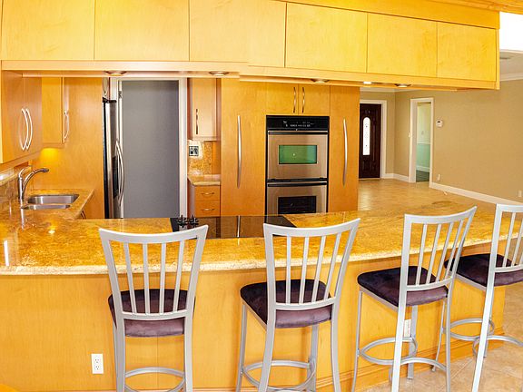 This photo shows the kitchen, laundry room access, dining area, living room, main entrance, and the hallway leading to the master bedroom, second bedroom, and shared bathroom.