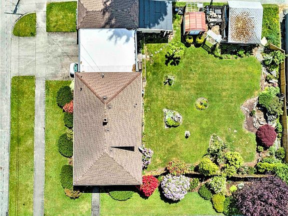 Great overhead view of the entire property showing mature landscaping, carport & covered patio too, shop + 2 more outbuildings and on the far right next to the Japanese maple there is a fish pond waiting to be used again!