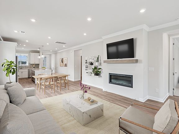 A modern, open-concept living room with a fireplace, a large TV mounted on the wall, and a dining ar