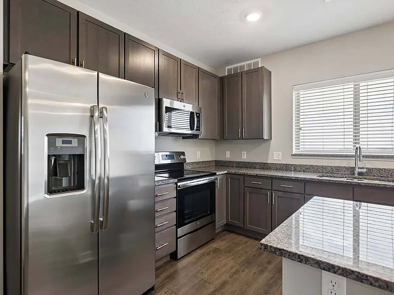 Rich wood cabinetry, gleaming stainless steel appliances, and expansive countertops create a kitchen that's equal parts sophisticated and functional.