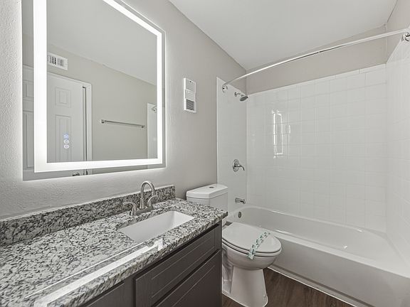 Modern bathroom with granite vanity and bathtub shower combination