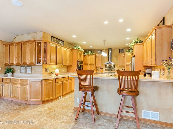 This kitchen is any chefs delight! Tons of Kraftmaid cabinets wrap around into the large eat in area- adding another 8+ feet of upper & lower cabinets & corian topped counter-space. Plus center island. Room for 4 chairs at the raised breakfast bar!