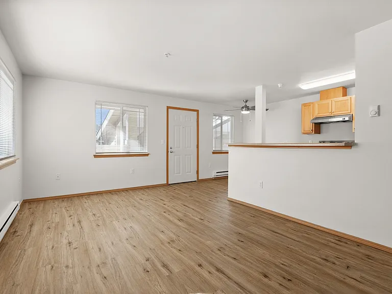 Bright and airy open-plan living area featuring large windows, wood flooring, and a modern kitchen with wooden cabinetry. Bright and airy open-plan living area featuring large windows, wood flooring, and a modern kitchen with wooden cabinetry.