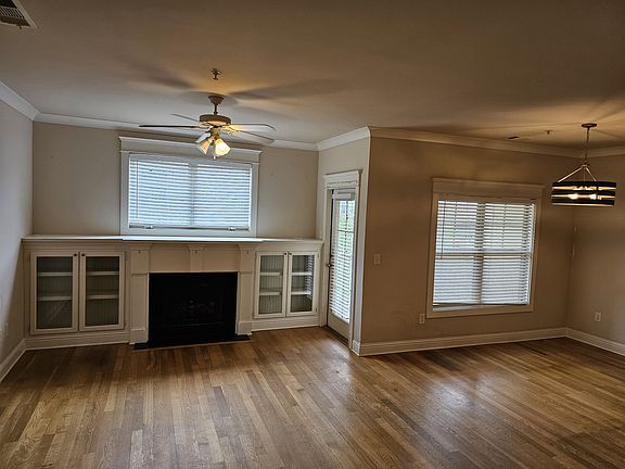 Elegant upstairs living room featuring hardwood floors, built-in cabinetry, and a central fireplace with direct access to a private covered patio overlooking the Beltline, perfect for relaxing or entertaining.