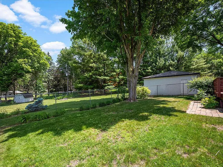 View of wooded backyard with storage shed, 2 stall garage and fire pit