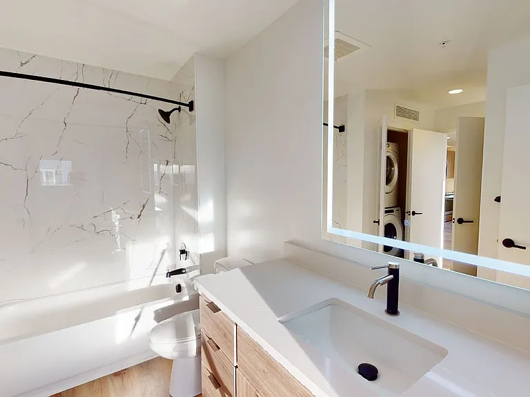 Apartment bathroom with wood-style flooring and LED vanity mirror.